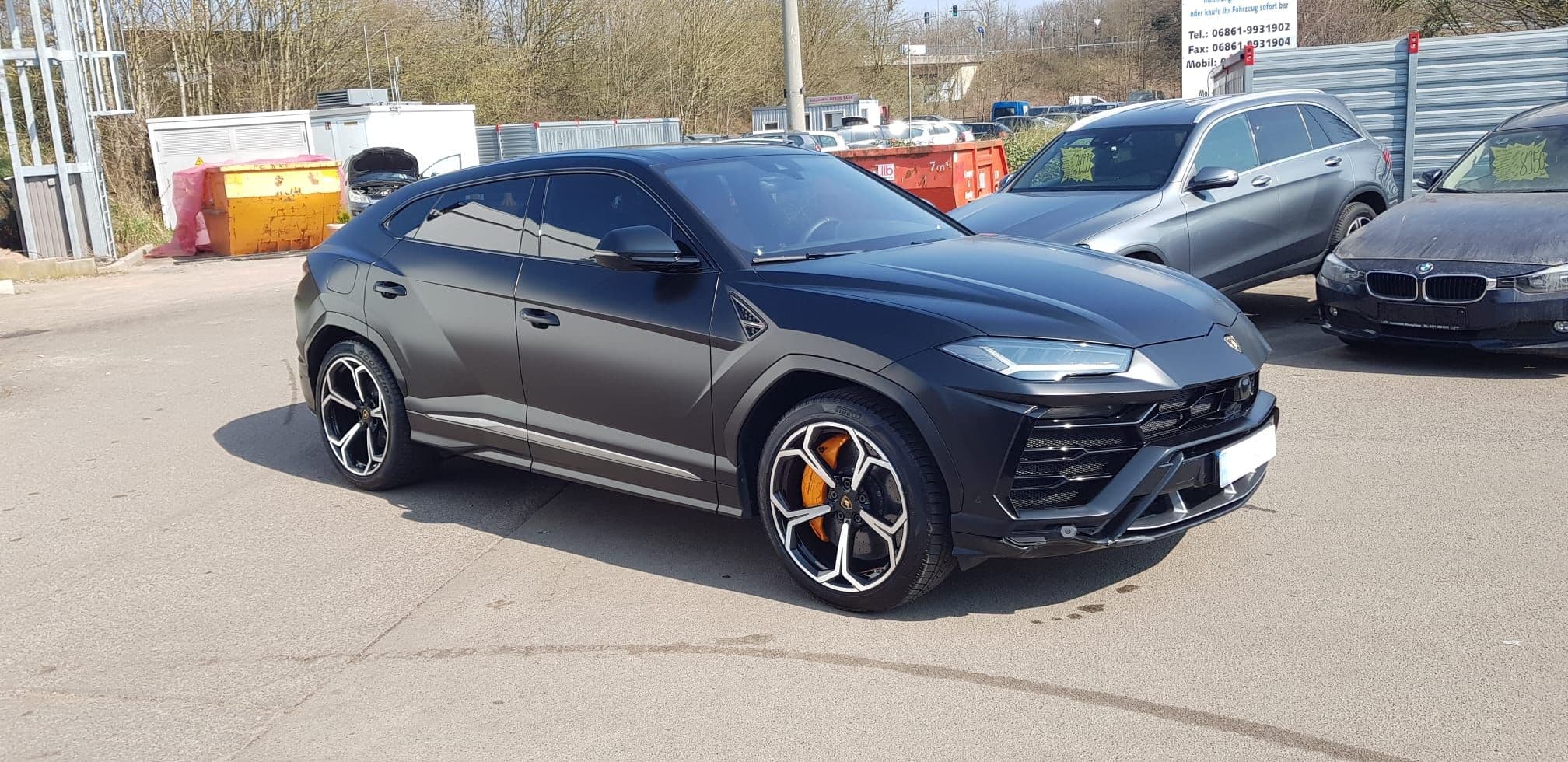Dunkler Lamborghini Urus im Freien vor der Halle