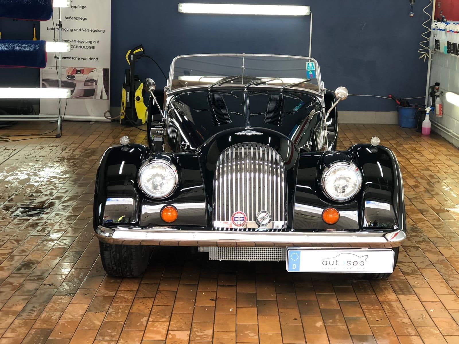 Schwarzer Oldtimer-Roadster mit Chromgrill und Speichenrädern in der Halle
