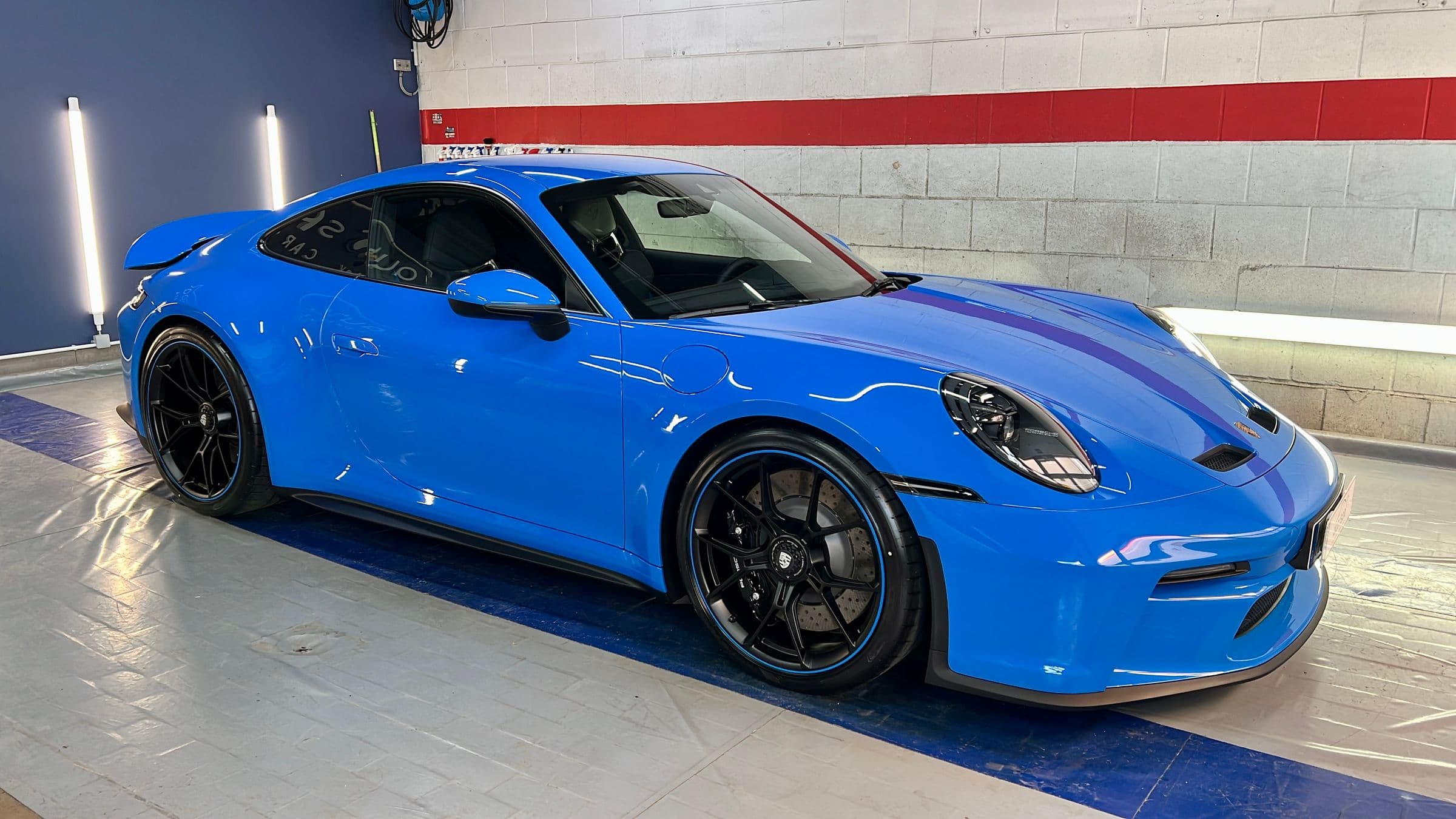 Blauer Porsche 911 in der Halle, der Lack spiegelt die Deckenbeleuchtung